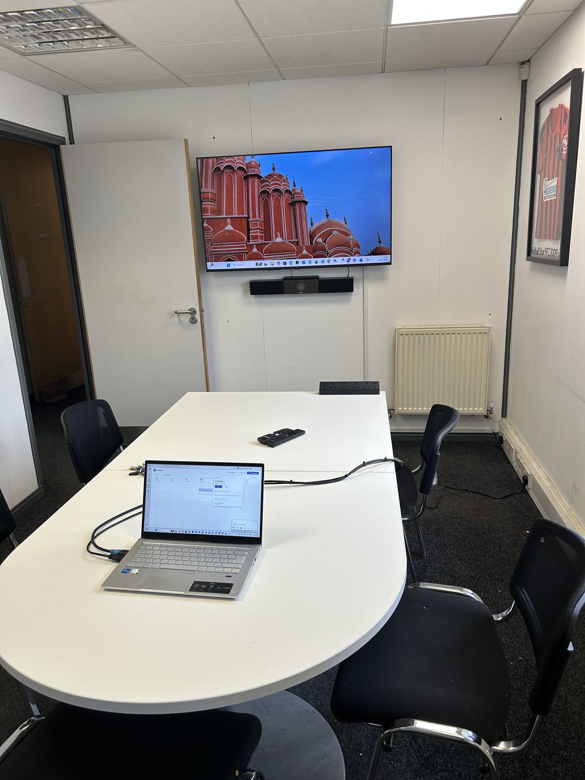 Second meeting room fitted with the same wall-mounted TV and Poly video bar setup