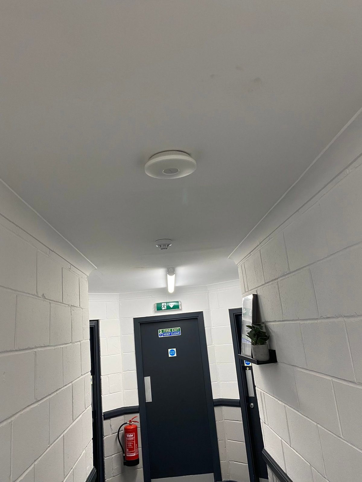 Ceiling-mounted wireless access point installed in the building's communal corridor